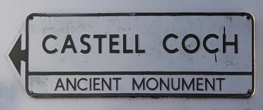 Old, worn sign that reads Castell Coch Ancient Monument