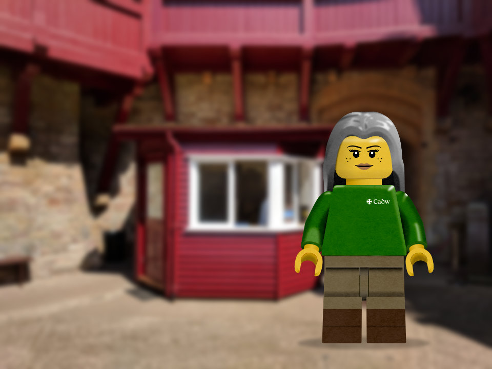 Illustration of a Cadw volunteer as a Lego minifigure with Castell Coch in the background