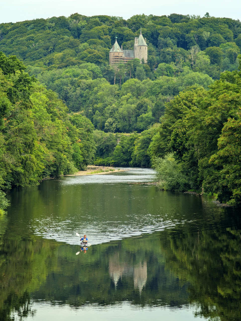 Castell Coch above the River Taff with a kayak paddling in the foreground.