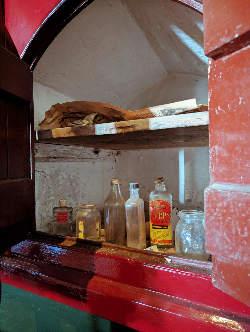 A small cupboard in Castell Coch that contains some old jars and newspaper from the 1950s.